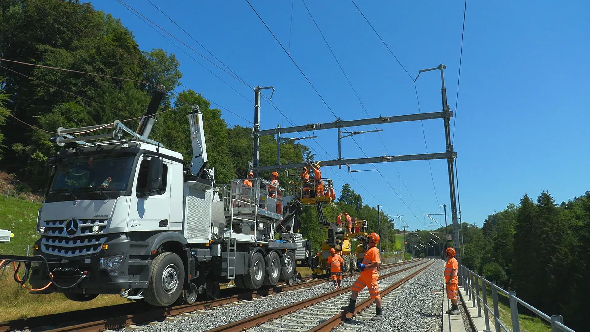 Schienengängiger Lkw mit Hubarbeitsbühne im Gleis: Monteure arbeiten von Arbeitskörben aus an der Oberleitung einer elektrifizierten Strecke