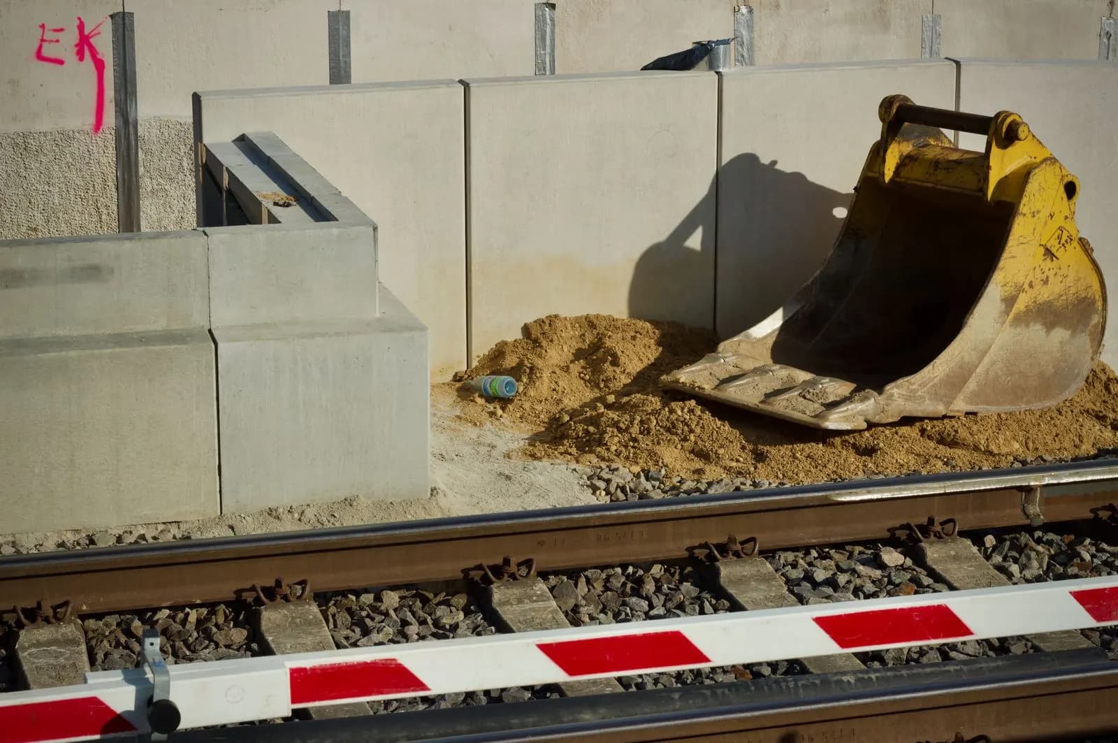 Baggerlöffel neben dem Gleis auf einer Bahnbaustelle