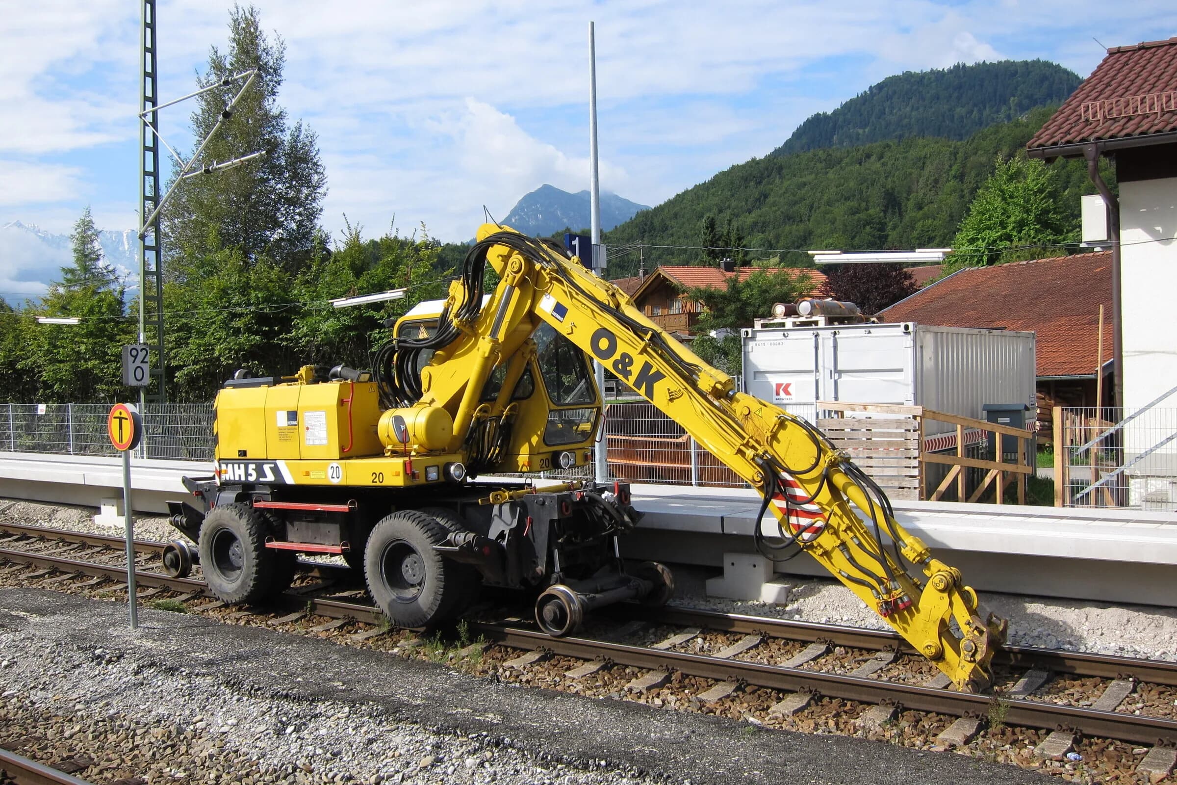 Zweiwege-Materialumschlagbagger (O&K) mit ausgefahrenem Ausleger am Bahnsteig